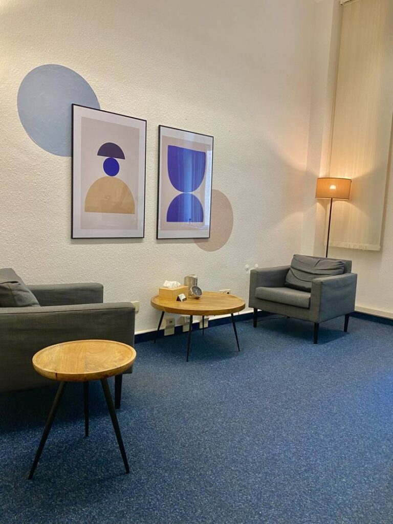 Behandlungsraum mit blauen Kunstdrucken, Sesseln und Stehlampe in der Praxis für Psychotherapie Mainzer Straße