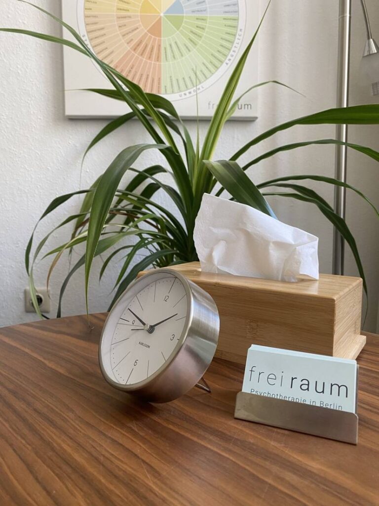 Tisch mit Uhr, Taschentuchbox und Visitenkarten von Freiraum Psychotherapie im Behandlungsraum