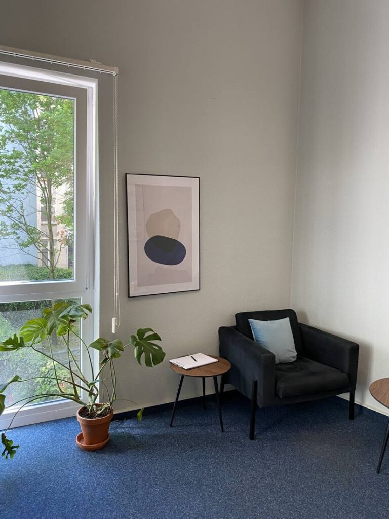 Sessel mit Kissen am Fenster mit Blick ins Grüne, Monstera-Pflanze, Praxis Mainzer Straße in Friedrichshain